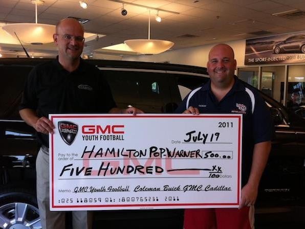 two employee holding youth football cheque